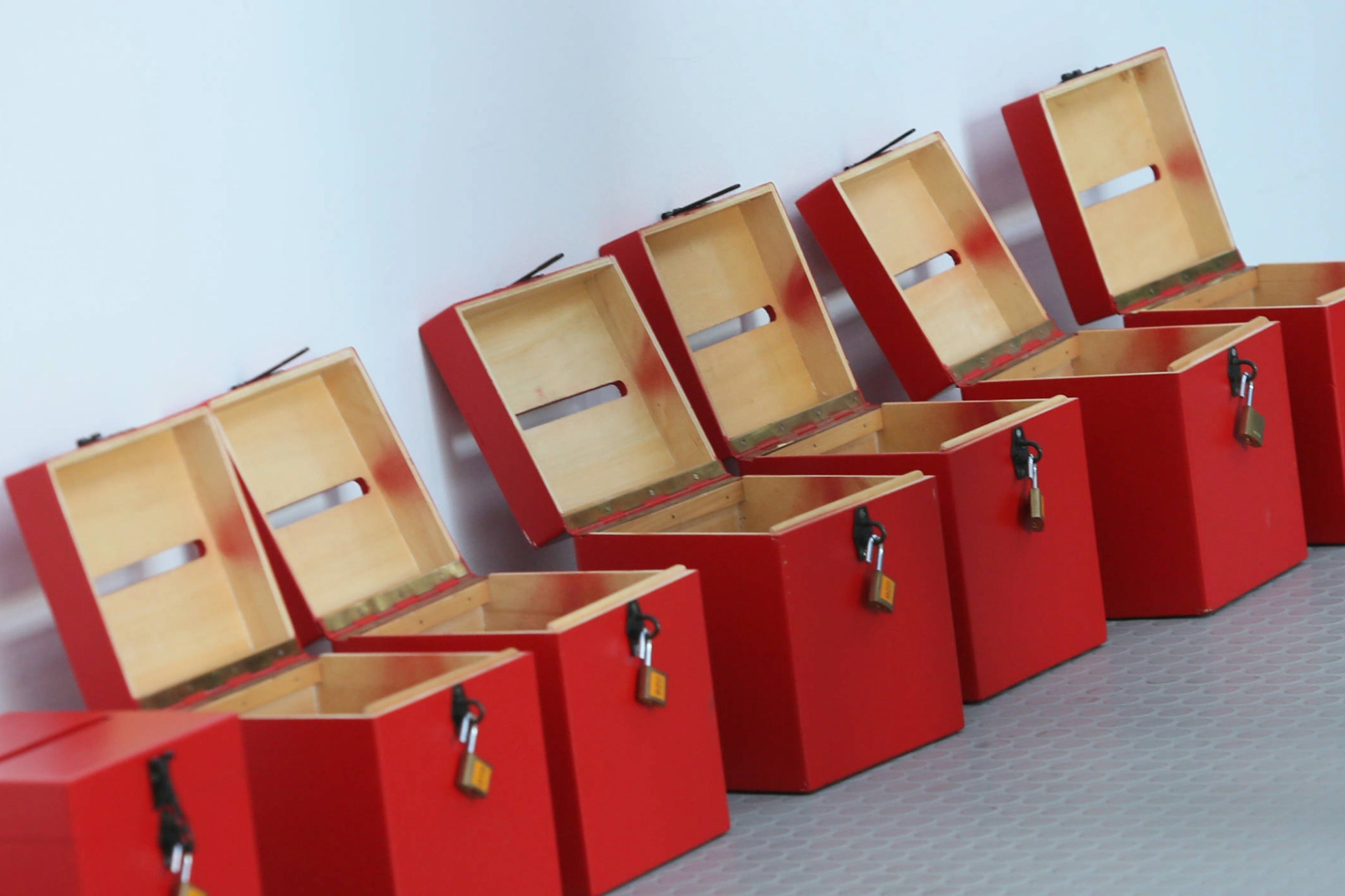 Offene Wahlurnen in rot stehen vor einer weißen Wand.