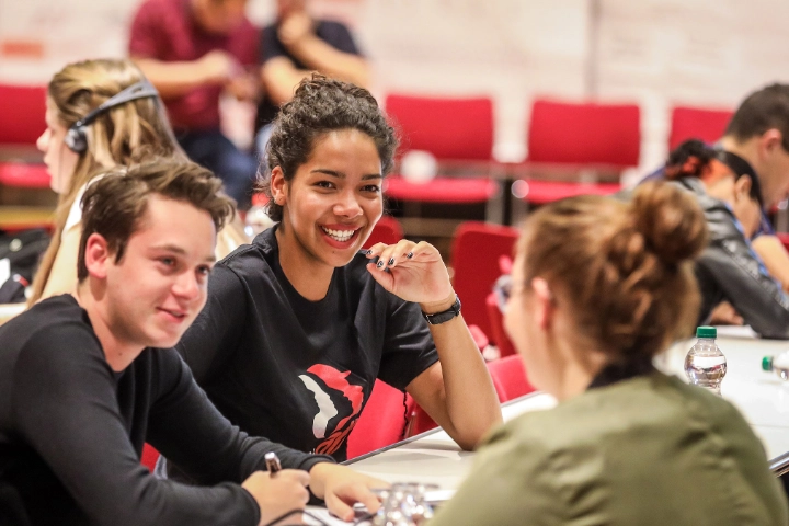 Eine Gruppe junger Menschen sitzt bei einer Konferenz zusammen und unterhält sich.
